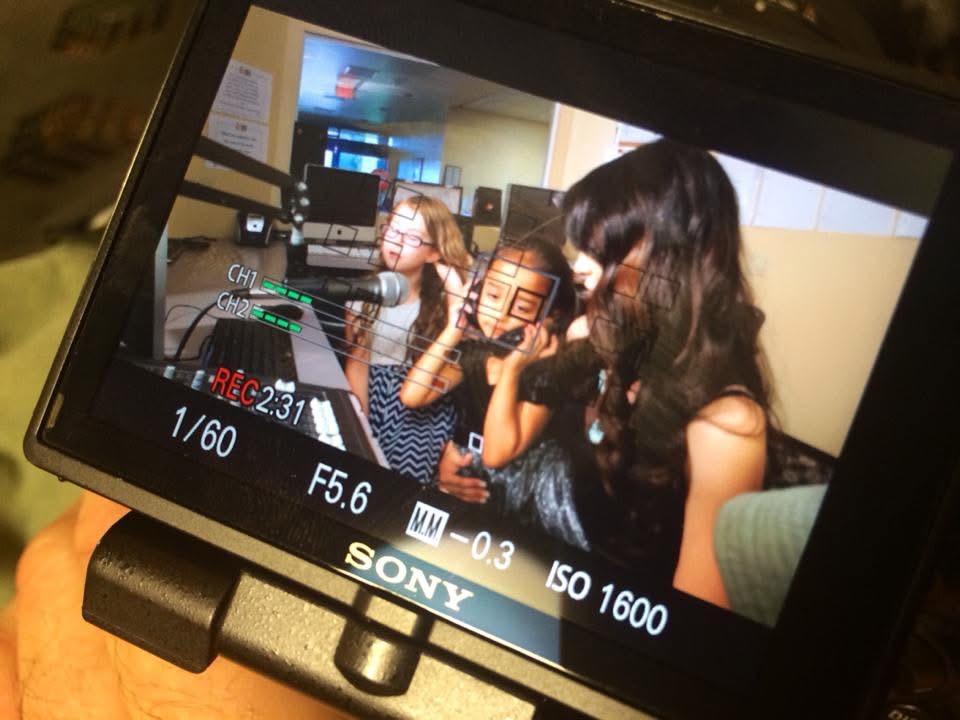 Arya Sitara Bhardwaj — the youngest member of KidStarRadio (age 3), the platform that launched Women Investing in Women & Girls in 2014. Pictured with green VoiceAmerica headphones in the radio studio alongside co-hosts Maddie Rose Holler and Michelle Jaffee — Women Investing in Women & Girls Radio Show, VoiceAmerica Kids, Clinton Global Initiative-ASU, Scottsdale, Arizona, March 2014.