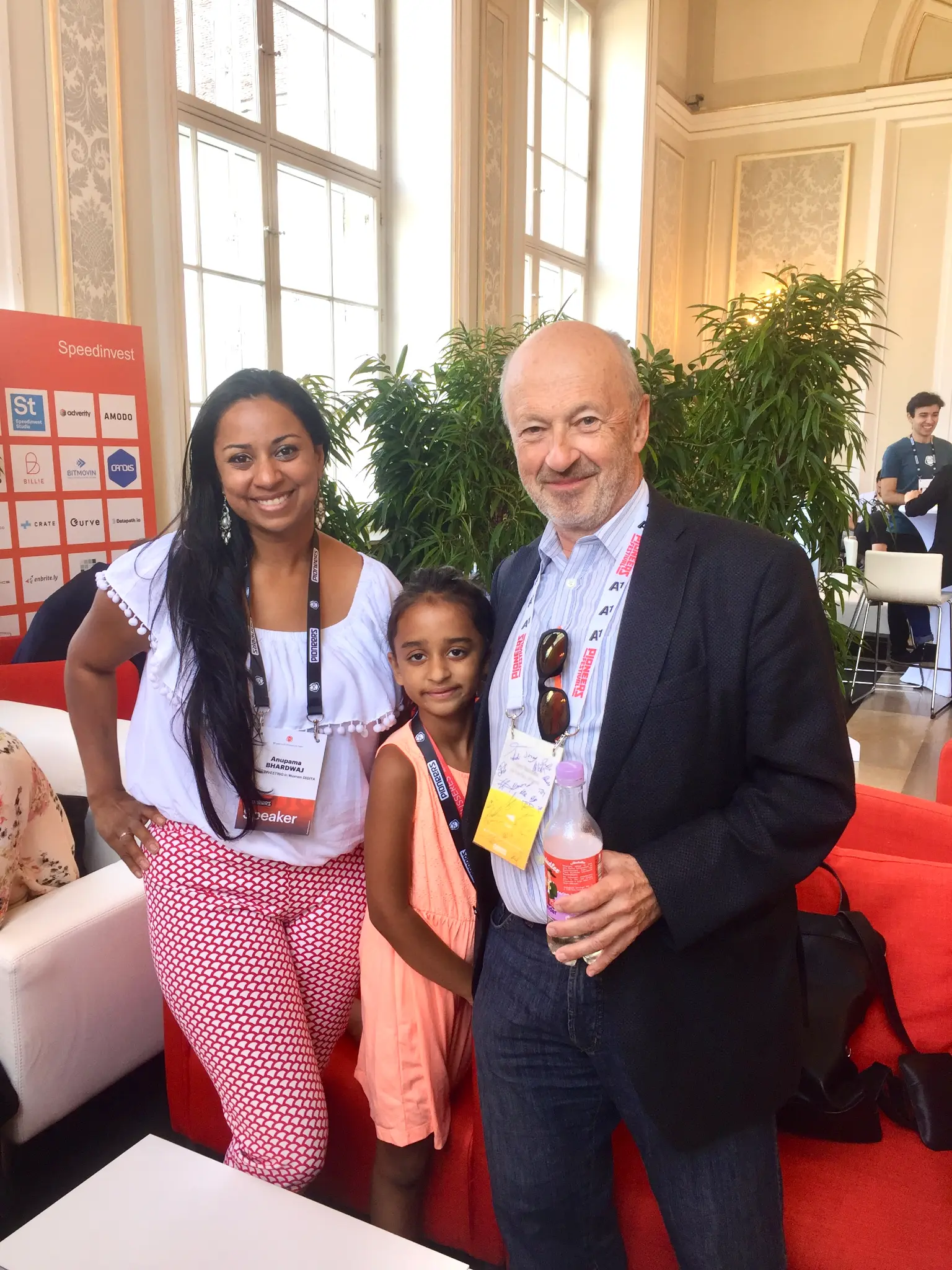 Anu & Arya Bhardwaj with Dr. Johann 'Hansi' Hansmann — Austria's most renowned business angel, Best European Early Stage Investor (EBAN 2016), President of the Austrian Angel Investors Association, and head of the Hans(wo)men Group (100+ investments; exits include Runtastic & Shpock). Anu's badge reads 'Speaker'. Speedinvest lounge, Pioneers '17, Hofburg Imperial Palace, Vienna, June 2017.