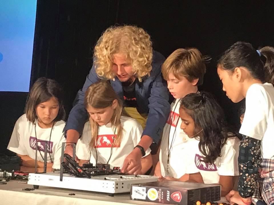 Krypto for Kids hands-on crypto mining workshop — instructor guiding children at the mining rig station, Blockchain on the Beach, Laguna Beach 2018