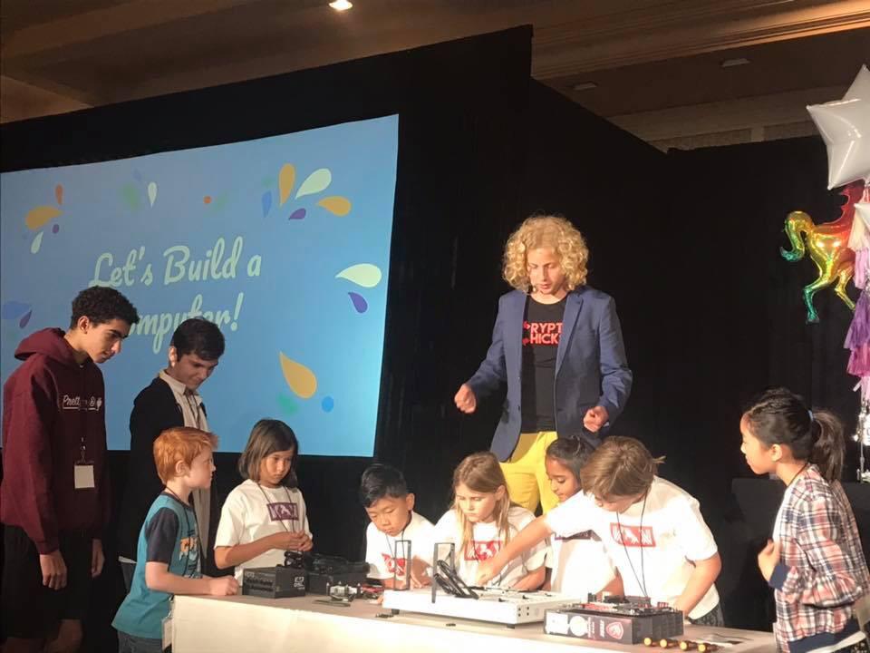 Let's Build a Computer! — Krypto for Kids hands-on computer-building workshop, Blockchain on the Beach, Laguna Beach 2018. Arya Bhardwaj (center, in blue blazer) guides children through building a computer from components.