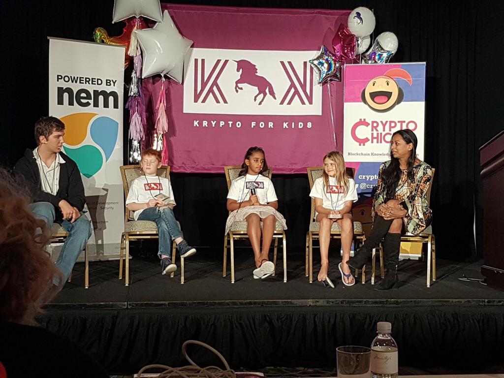 Krypto for Kids panel discussion — young innovators on stage with Anu Bhardwaj (right), NEM and CryptoChicks banners, Blockchain on the Beach, Montage Resort Laguna Beach, November 2018.