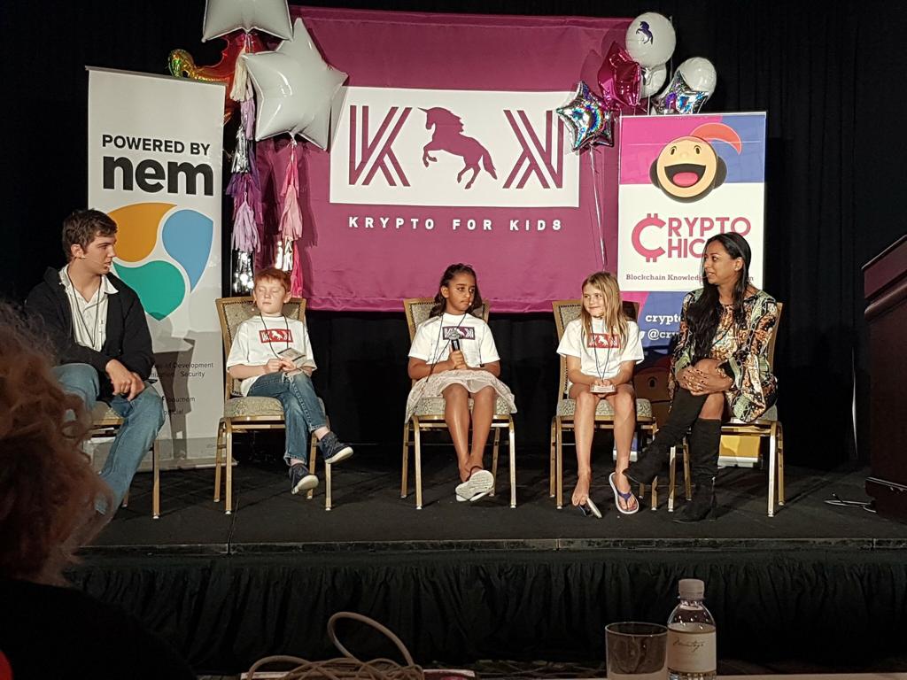 Krypto for Kids panel on stage — Arya Bhardwaj (center) with fellow young innovators, Anu Bhardwaj, NEM & CryptoChicks banners, Montage Resort Laguna Beach, November 2018